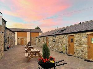 a patio with wooden benches and tables with a sunset at Peewit Cottage-Ukc6986 in Castleside