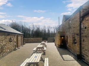 a row of wooden benches sitting next to a building at Peewit Cottage-Ukc6986 in Castleside