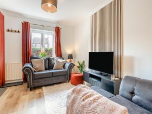 a living room with a couch and a flat screen tv at Star Cottage in Ringwood