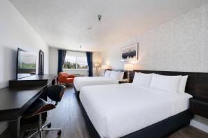 a hotel room with two beds and a desk at Hotel International in Lynnwood