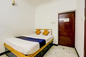 a bedroom with a bed and a wooden door at SPOT ON JAYAM RESIDENCY in Chennai