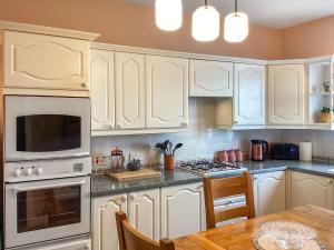 a kitchen with white cabinets and a wooden table at Seaspray in Buckie
