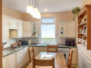 a kitchen with white cabinets and a table and a window at Seaspray in Buckie