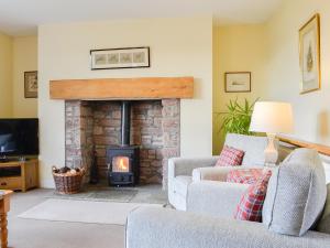 a living room with a fireplace with two couches at Osprey Cottage - Uzq in Kirkton of Airlie