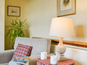 a lamp sitting on a table next to a chair at Osprey Cottage - Uzq in Kirkton of Airlie