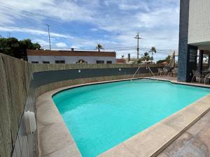 a large blue swimming pool next to a fence at Tropical Praia Hotel in Aracaju