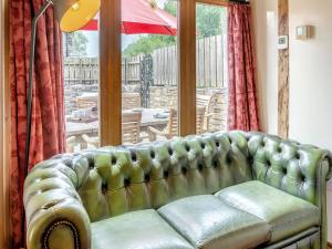 a green couch sitting in front of a window at Wern Farm Barn in Cwm-du