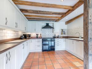 a kitchen with white cabinets and a tile floor at Wern Farm Barn in Cwm-du