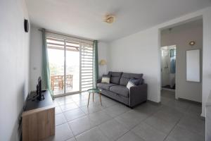 a living room with a couch and a large window at Appartement bois de chaumes in Cayenne