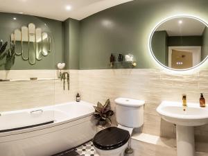 a bathroom with a tub sink and a toilet and a mirror at The Wharf in Warwick