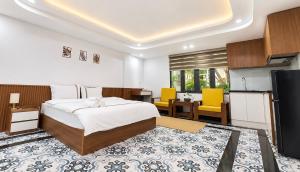 a bedroom with a bed and a kitchen with yellow chairs at Han House's Apartment in Danang