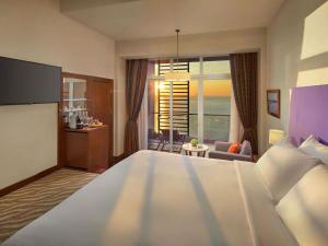 a bedroom with a large bed and a living room at Novotel Nha Trang in Nha Trang