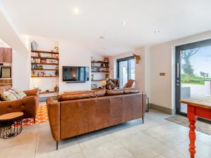 a living room with a brown leather couch and a tv at Ty Eufron in St. Davids