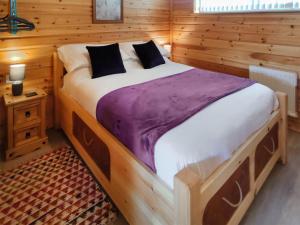 a bedroom with a large bed in a wooden room at Nature's Nook in Brundall +8 photos
