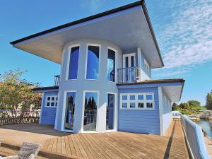 a large blue house with a large window on a deck at Flag House - Ukc7074 in Brundall +5 photos