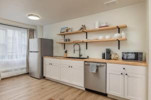 a kitchen with white cabinets and a stainless steel refrigerator at Downtown 1 Bedroom Flat with Views in Anchorage