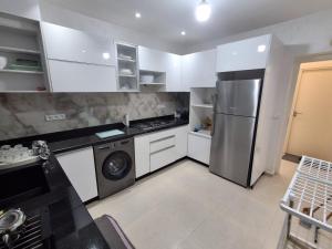 a kitchen with a stainless steel refrigerator and white cabinets at Appartement Residence Tafoult IMIOUADDAR in Agadir nʼ Aït Sa