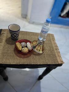 a table with a bottle of water and a plate of rocks at maison bleu hajja in Tangier