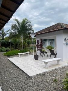 a patio with two benches and a house at Hotel do Valle in Tijucas