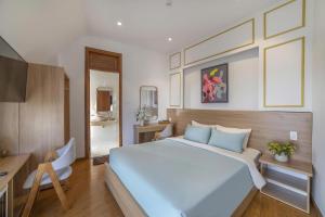 a bedroom with a large white bed and a desk at Dalat Hotel & Villa by Pham Gia in Xuan An
