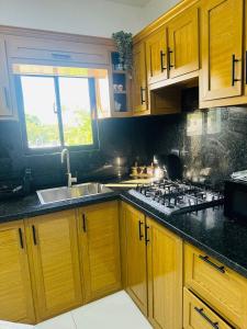 a kitchen with wooden cabinets and a sink and a stove at Luma Residence in San Felipe de Puerto Plata