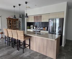 a kitchen with a counter with chairs and a refrigerator at Quiet Homestay Ulladulla in Ulladulla