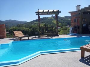 a swimming pool with a pergola next to a house at Recanto do SOL in Imaruí