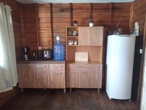 a kitchen with a refrigerator and wooden walls at Recanto do SOL in Imaruí
