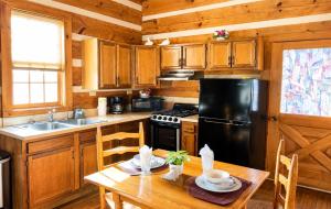 a kitchen with a table and a black refrigerator at Bearfoot Bungalow- Tiny Cabin Getaway in Sevierville