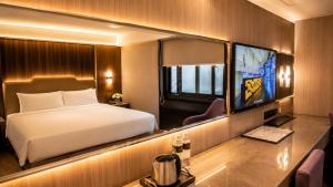 a hotel room with a bed and a tv at The Cloud Hotel in Kaohsiung