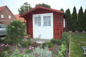 a red shed with a white door in a yard at Ferienhaus Victoria in Norden