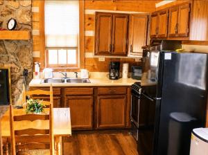 a kitchen with wooden cabinets and a black refrigerator at Bearfoot Bungalow- Tiny Cabin Getaway in Sevierville +2 photos