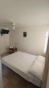a white bed in a room with a table at Hosp Norte Los Organos in Los Órganos