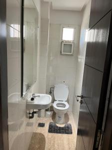 a white bathroom with a toilet and a sink at Cozy Beach Apartment Diar Mansour Rabat in Rabat +9 photos