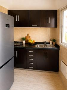 a kitchen with black cabinets and a stainless steel refrigerator at Cozy Beach Apartment Diar Mansour Rabat in Rabat
