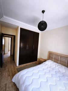 a bedroom with a white bed and a black cabinet at Cozy Beach Apartment Diar Mansour Rabat in Rabat