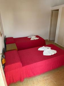 two beds in a room with red sheets at Malibu in Termas de Río Hondo +4 photos
