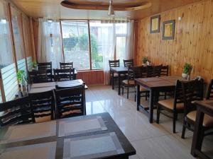 a restaurant with wooden walls and tables and chairs at Snow Range Cottages in Manāli