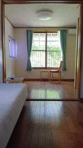 a bedroom with a bed and a large window at 民泊kururu 個室 鍵付き朝パン付きライダー用ガレージ有り in Nishidani