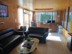 a living room with a leather couch and a table at Snow Range Cottages in Manāli