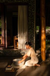 a woman sitting on the floor next to a bowl at Menjaga Bay in Labuan Bajo