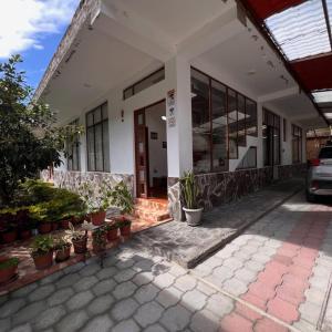 a building with potted plants in front of it at Núba Hospedaje in Baños