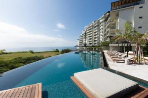 an infinity pool at a resort with chairs and the ocean at The Friendly Condo by AcoModo Punta Caelo in El Nance
