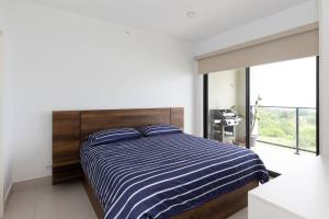 a bedroom with a bed with a blue and white striped comforter at The Friendly Condo by AcoModo Punta Caelo in El Nance +37 photos