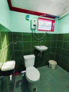 a green tiled bathroom with a toilet and a sink at Tugbongan North Siargao in Burgos