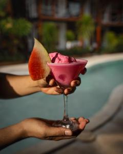 a person holding a drink with a slice of watermelon at Voodoo Gili in Gili Trawangan +37 photos