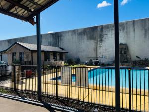 a view of a swimming pool behind a fence at Pacific Motel Taree in Taree