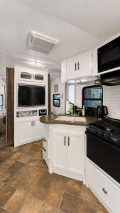 a kitchen with white cabinets and black appliances at 2-bedroom Camper Trailer Cottage #3 in Dillon