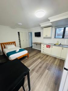 a bedroom with a bed and a kitchen with a sink at Pacific Motel Taree in Taree