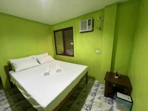 a green bedroom with a white bed and a window at Jaliha Homestay in San Isidro